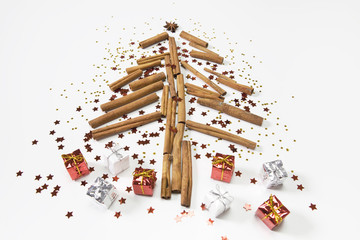 Christmas tree made of cinnamon sticks, cones, oranges, shiny stars and presents. White background