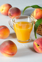 A glass with peach juice and ripe peaches.