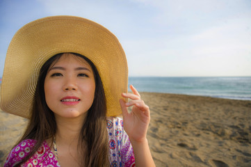 close up lifestyle portrait of young beautiful and happy Asian Korean tourist woman in Summer hat smiling cheerful at tropical island beach looking at the camera