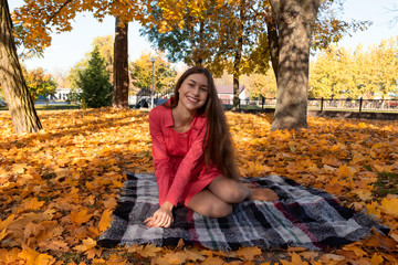 Beautiful brunette girl in pink dress in autumn park.