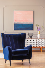 Obraz premium Retro, navy blue armchair in an elegant living room interior with an abstract painting on a wall with molding