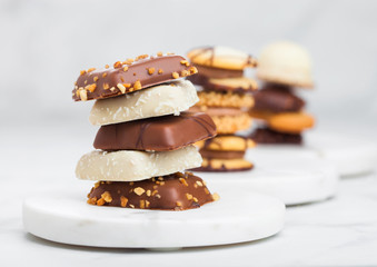 Luxury belgian chocolate and biscuit cookies selection on marble coasters and white kitchen table...