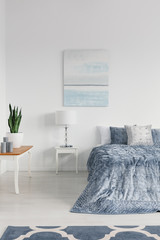 Candles and green plant in white pot on the table in elegant new york style bedroom in stylish apartment, real photo