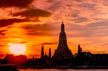 Wat Arun Ratchawararam at sunset with beautiful  orange sky and clouds. Wat Arun buddhist temple is the landmark in Bangkok, Thailand. Attraction art and ancient architecture in Bangkok, Thailand.