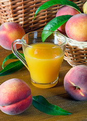 A glass with peach juice and ripe peaches.