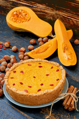Autumn tart with goji berry decorated with hazelnuts and cinnamon on the black rustic wooden background. Traditional dessert - pumpkin pie for Thanksgiving holiday. Side view