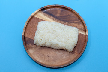 close up of sticky rice in wooden plate on blue background