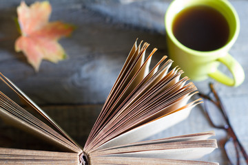 Open book autumn leaves tea and glasses abstract background on wooden boards
