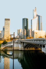 Naklejka premium Cityscape view of La Defense financial district with skyscrapers and old bridge during the morning light in Paris