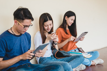 Group of Asian college student using tablet and mobile phone outside classroom. Happiness and Education learning concept. Back to school concept. Teen and people theme. Outdoors and Technology theme.
