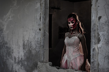 Female zombie corpse standing in front of grunge wall in abandoned house. Horror and Ghost concept. Halloween day festival and scary movie theme. Haunted house theme. Dark tone film