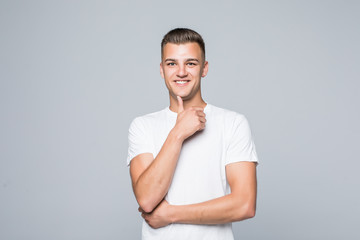 Looking forward. Handsome smiling man standing on white isolated background and touching his chin with hand