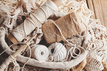 Needlework, macrame, knitting. Yarn and thread of natural colors in a wicker basket. Women's hobby. - obrazy, fototapety, plakaty