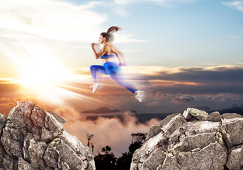 Woman jump through the gap between hills over sunset background.