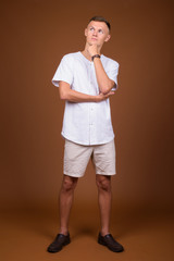 Fototapeta na wymiar Young man wearing white shirt against brown background