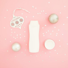 Christmas composition. Decoration and confetti with shampoo bottle on pink background. Flat lay, top view. Beauty concept