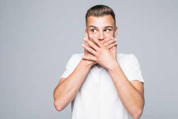 Vertical shot of surprised terrifired hipster guy covers mouth in shock, looks upwards, isolated over white background
