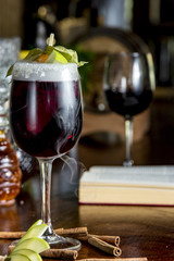 Glass of red wine cocktail with fruits and dry ice, on wooden table