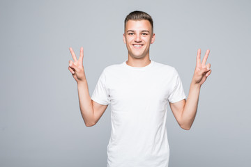 Smiling Bearded man in shirt which showing peace signs and looking at camera isolated gray...