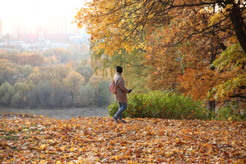 Student with a phone in his hand on the background of a autumn Park.
