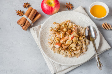 Fototapeta premium Oatmeal with fresh apples, nuts and cinnamon for Breakfast on the table, close-up, horizontal