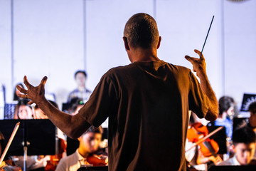 Back view of a male conductor directiing his band at a local school