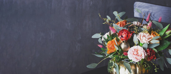 Fototapeta na wymiar Autumn floral bouquet in punpkin vase on black chair, banner