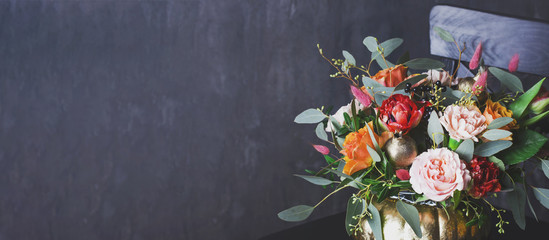 Autumn floral bouquet in punpkin vase on black chair, banner