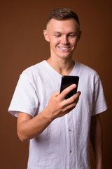 Young man wearing white shirt against brown background