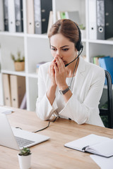 stressed support operator working with headset and laptop in call center