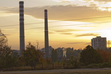 Fototapeta na wymiar TPP thermal power plant on a sunrise. Refinery with smokestacks. Smoke from factory pollutes the environment. High red and white tower of CHPP. TPP produce steam for electric power. Pollution, climate