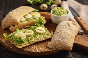 Avocado sandwich ciabatta with quail eggs.