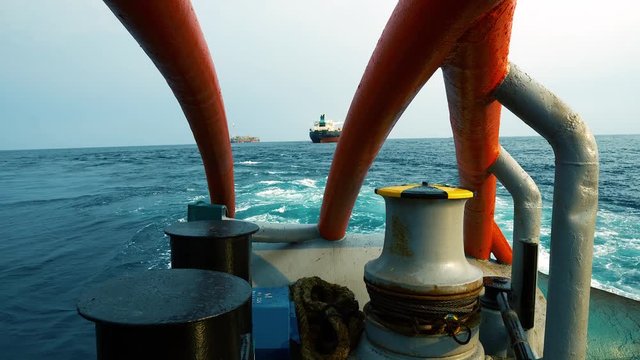 Anchor-handling Tug Supply AHTS vessel during dynamic positioning DP operations near FPSO tanker. Vessel is doing static tow tanker lifting. Ocean tug job.