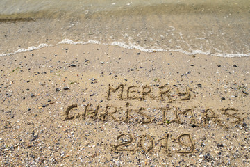 Merry Christmas 2019 written on tropical beach sand, copy space. Holiday concept, top view