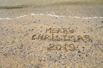 Merry Christmas 2019 written on tropical beach sand, copy space. Holiday concept, top view