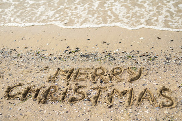 Merry Christmas written on tropical beach sand, copy space. Holiday concept, top view