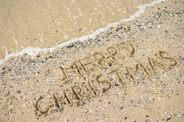 Merry Christmas written on tropical beach sand, copy space. Holiday concept, top view