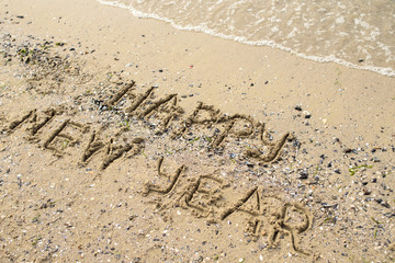Happy new year written on tropical beach sand, copy space. Holiday concept