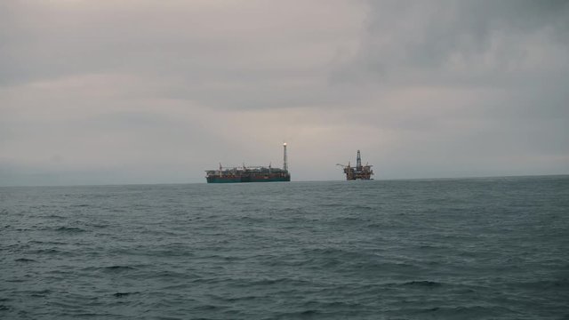 FPSO tanker vessel near Oil Rig platform. Offshore oil and gas industry. Flare is burning with smoke. Environmental pollution