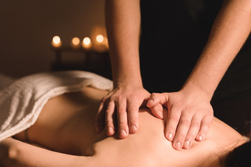 Close up Male manual worker doing spa massage to a young girl in a dark room