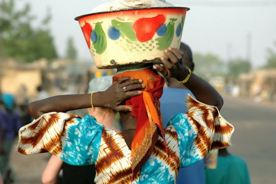Femme de dos tunique bariolée et bassine colorée sur la tête, Burkina Faso, Afrique
