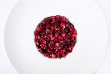 Salad with beets. Vinegret is a traditional Russian salad made from beets and vegetables in a white plate. The background is white. Top view. Copy space. Horizontal shot.