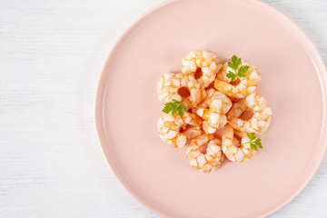 Boiled shrimp and parsley on a pink plate. Macro. The concept of healthy eating. The background is white. Copy space. Horizontal shot. Top view.