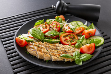 Vegetable salad and grilled chicken on a black background. Healthy food. Diet.