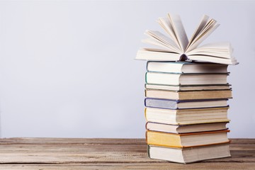 Stacked books on desk at library - obrazy, fototapety, plakaty