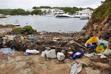 Plastic waste washed up with the sea weed in small cove in Menorca 