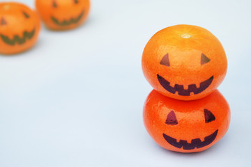 Funny orange mandarins or tangerines pumpkin painted in the form of icons of Halloween on the light backround