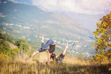 Giovane coppia pratica acroyoga e yoga all'aperto in montagna al parco