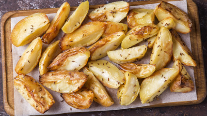 Baked potato with cumin on wooden board. Closeup