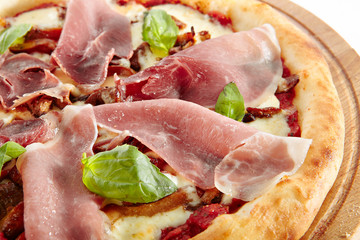 Pizza with Parma Ham, Porcini Mushrooms, Mozzarella Cheese, Fresh Basil, Cherry Tomatoes, Pesto and Tomato Sauce Isolated on White Background. Traditional Italian Whole Flatbread on Wood Close Up